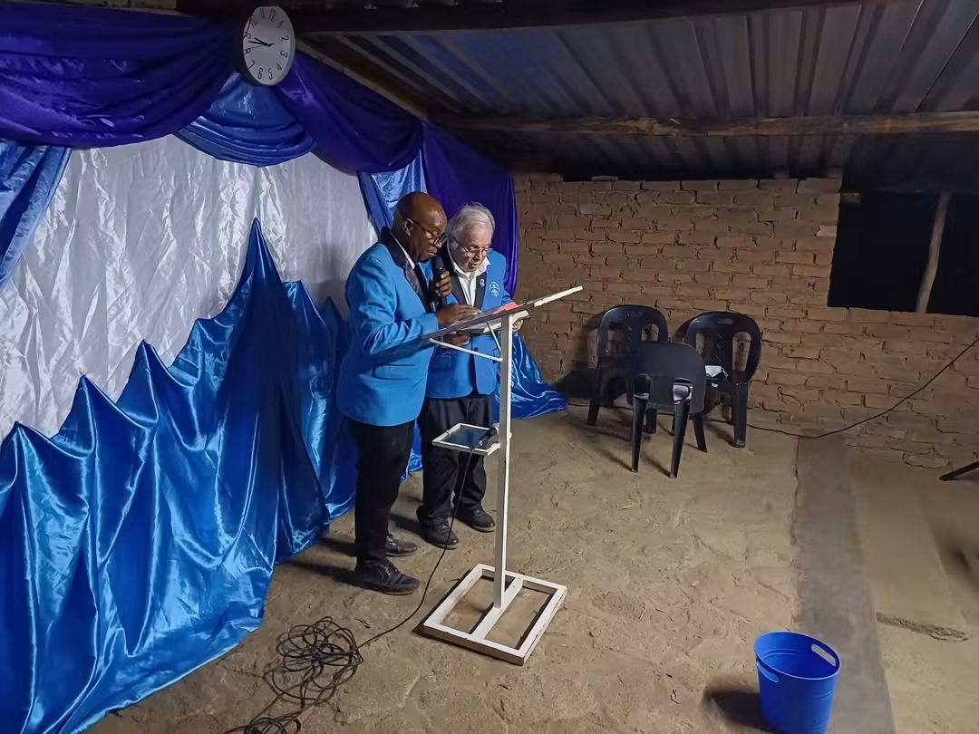 Two CFM church leaders in blue jackets ministering at the pulpit
